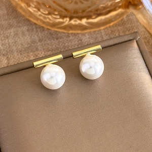 Detail of minimalist gold bar earrings with dangling white pearls on jewelry box
