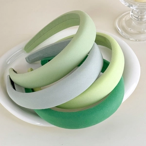 Close-up detail of four shades of green sponge headbands in a ceramic tray