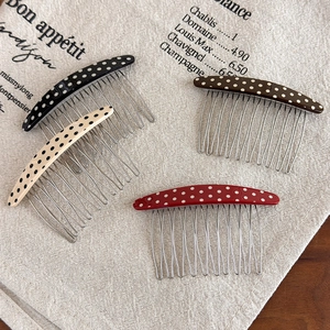 Close-up of four retro polka dot hair combs with silver wavy metal teeth on linen