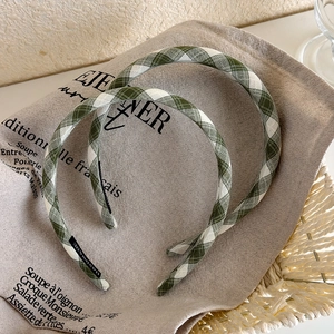 Detail of green plaid headband with handmade label on French style canvas background