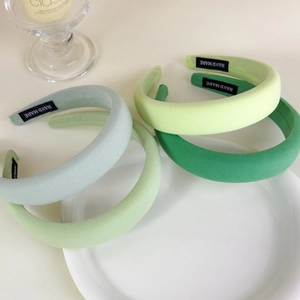 Detail of green handmade sponge headbands showing fabric texture and inner labels