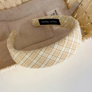 Détail d'un serre-tête à carreaux en tissu beige avec une étiquette faite à la main