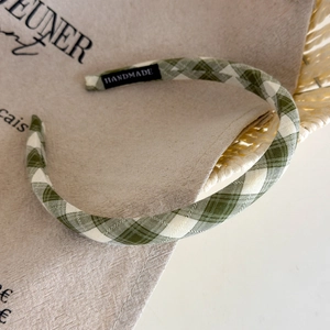 Detailed view of green plaid headband featuring a handmade label on fabric