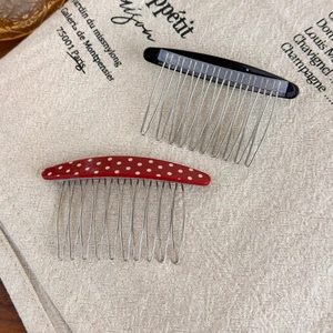 Detail view of vintage polka dot and black acetate curved hair combs on linen cloth
