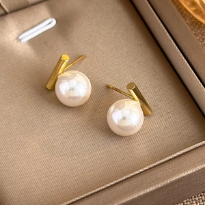 Detail of minimalist gold column earrings with large white pearls on silk texture