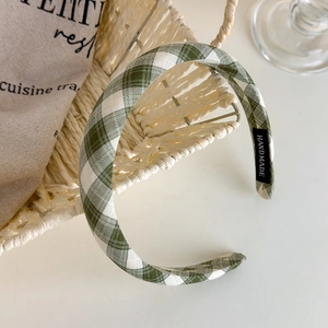 Detail of green and white plaid headband with handmade label on white table