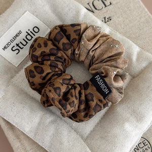 Detail of leopard print scrunchie with metallic star charm and fashion label