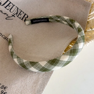 Detail of green and white gingham headband with handmade woven label and fabric texture