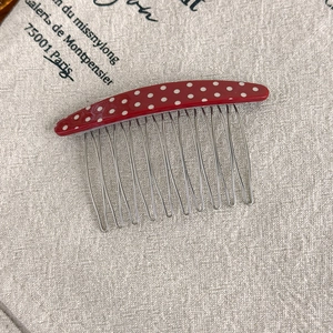 Close-up of red polka dot acetate comb with silver metal teeth for elegant hairstyling