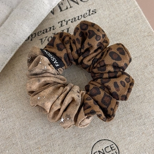 Detailed shot of leopard print scrunchie with silver star accents and Fashion label