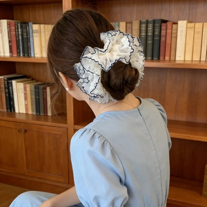 Chouchou géant en dentelle blanche de style rétro français avec bordure bleue sur un chignon