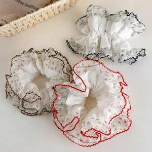 Détail de trois chouchous en maille florale avec bordure en dentelle sur fond blanc