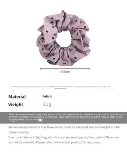 Détail d'un chouchou en tissu à fleurs violettes montrant le diamètre de 14 cm et la texture