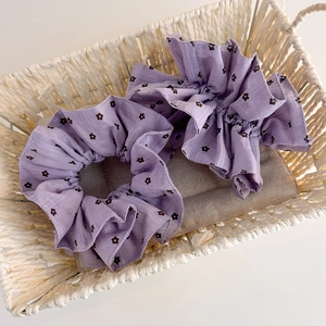 Gros plan de deux chouchous à fleurs violettes en tissu texturé dans un panier tressé