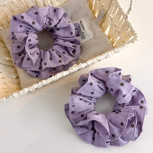 Détail de deux chouchous violets à motifs floraux noirs dans un panier blanc élégant