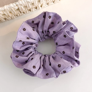 Détail du chouchou fleuri violet avec texture côtelée délicate et motif floral élégant