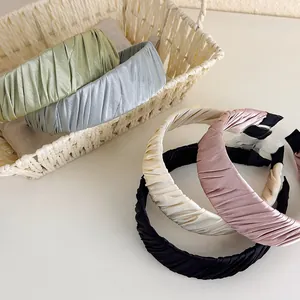 Detailed macro view of pleated satin headbands in green, blue, cream, pink, and black