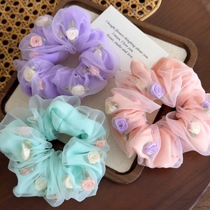 Trois chouchous fleurs en organza violet, rose et vert menthe sur plateau en bois