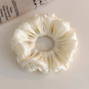 Detail of off-white pleated organza scrunchie with soft fabric texture and elegant sheen