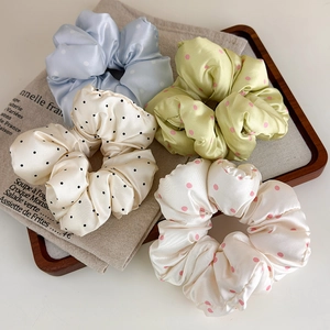 Lot de quatre chouchous en satin à pois en bleu pastel, vert et crème sur un plateau bois