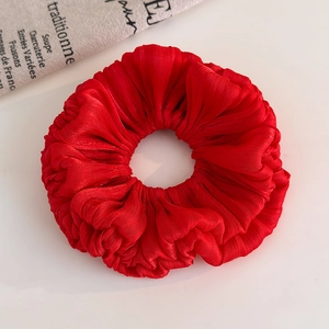 Detailed close-up of a red pleated organza scrunchie with silk sheen and ruffled texture