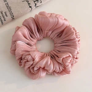 Detailed macro view of pink pleated satin scrunchie with a soft glossy texture and folds