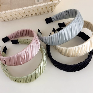 Detail showing various colors of pleated satin headbands in pink green and blue