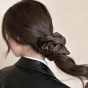 Detailed view of velvet leopard print scrunchie worn on a high ponytail with stylish outfit