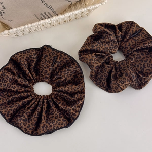 Close-up of velvet leopard print scrunchies with fine black hem and pleated texture