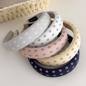 Detail of five floral print sponge headbands in pastel colors with Hand Made label
