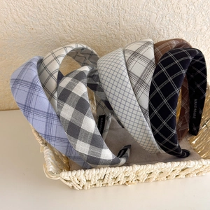 Detail view of plaid headbands set in a basket showing the handmade label and fabric texture