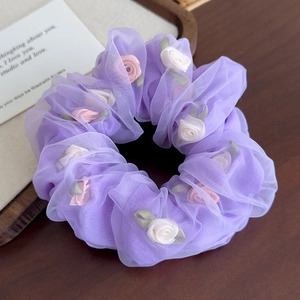 Détail d'un chouchou en organza violet avec roses 3D en tissu rose et blanc