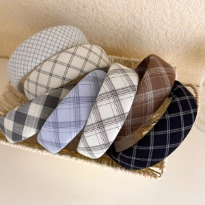 Detail shot of seven plaid padded headbands in various colors inside a woven basket