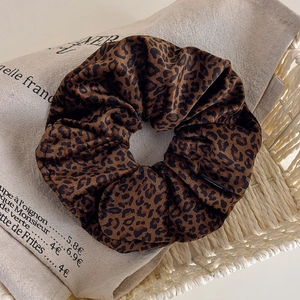 Close-up of velvet leopard print scrunchie placed in a white basket for a vintage aesthetic