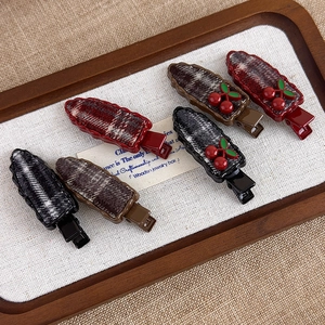 Retro red cherry hair clip set with vintage plaid patterns on a warm wooden tray