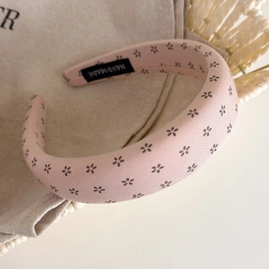 Close-up of pink floral padded sponge headband with handmade label on inner velvet lining