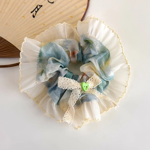 Detail of blue floral chiffon scrunchie with lace bow and green heart button