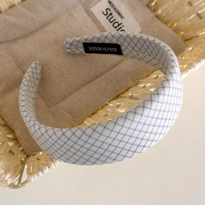 Detail of blue and white checkered padded headband featuring a woven Hand Made label