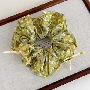 Detail eines floralen Haargummis mit gelben Seidenschleifen auf Vintage-Tablett
