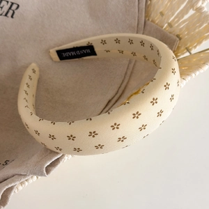 Detail of beige floral sponge headband with a handmade tag on soft cotton background