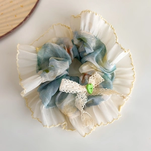 Detail of blue Monet oil painting style scrunchie with lace bow and green heart button