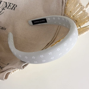 Close-up of light blue floral sponge headband with handmade label on a canvas bag