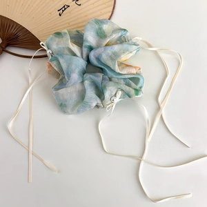 Detail of blue floral organza scrunchie with long cream ribbons and pearl accent