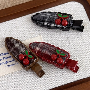 Detailed macro view of three cherry plaid hair clips in black, brown and deep red colors