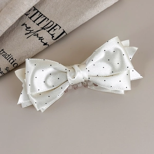 Dettaglio del fermaglio per capelli in raso bianco a pois con elegante fiocco