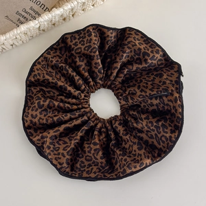 Detailed close-up of brown velvet leopard print scrunchie with soft fabric texture