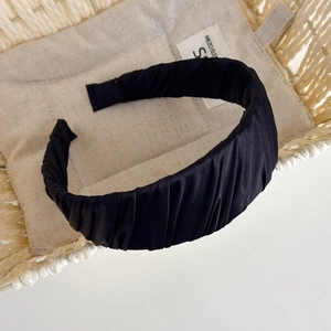 Close-up of black satin pleated headband with vintage texture on woven basket