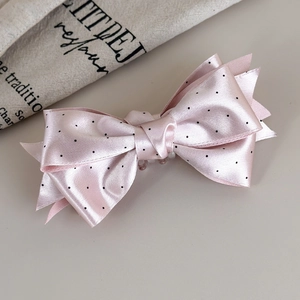 Dettaglio del fermaglio per capelli in raso rosa a pois con elegante fiocco a strati