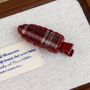Detail of red duckbill hair clip with vintage plaid fabric on soft beige background
