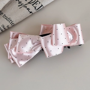Dettaglio del fermaglio per capelli in raso rosa a pois con fiocco multistrato
